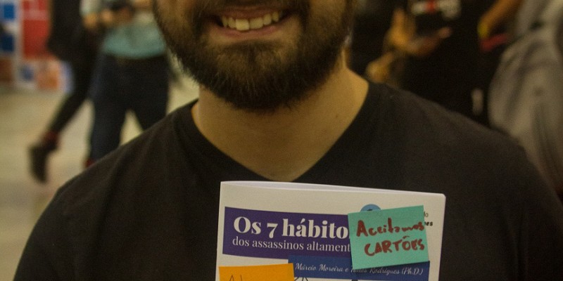O roteirista Márcio Moreira segura um exemplar de “Os 7 hábitos dos assassinos altamente eficazes”, zine lançado em parceria com Talles Rodrigues. (Foto: Filipe Pereira)