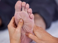 Senior man receiving foot massage from physiotherapist in clinic